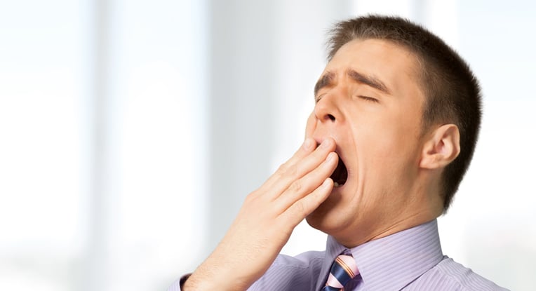 A middle aged man yawning because of his Sleep Apnea