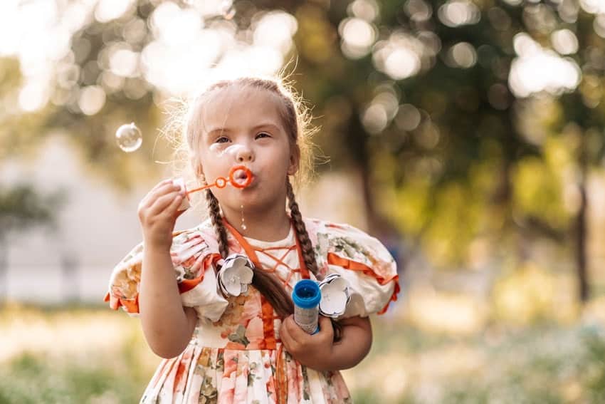 small child blowing bubbles outside