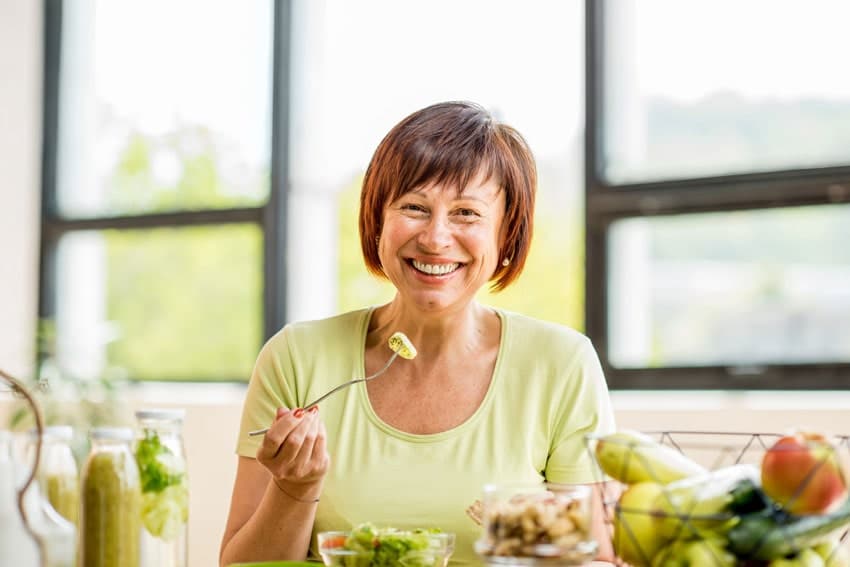 senior woman smiling and eating a salad
