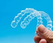 hand holding pair of invisalign up to the sky
