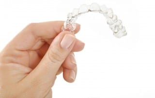 Close up of hand holding top of Invisalign clear brace