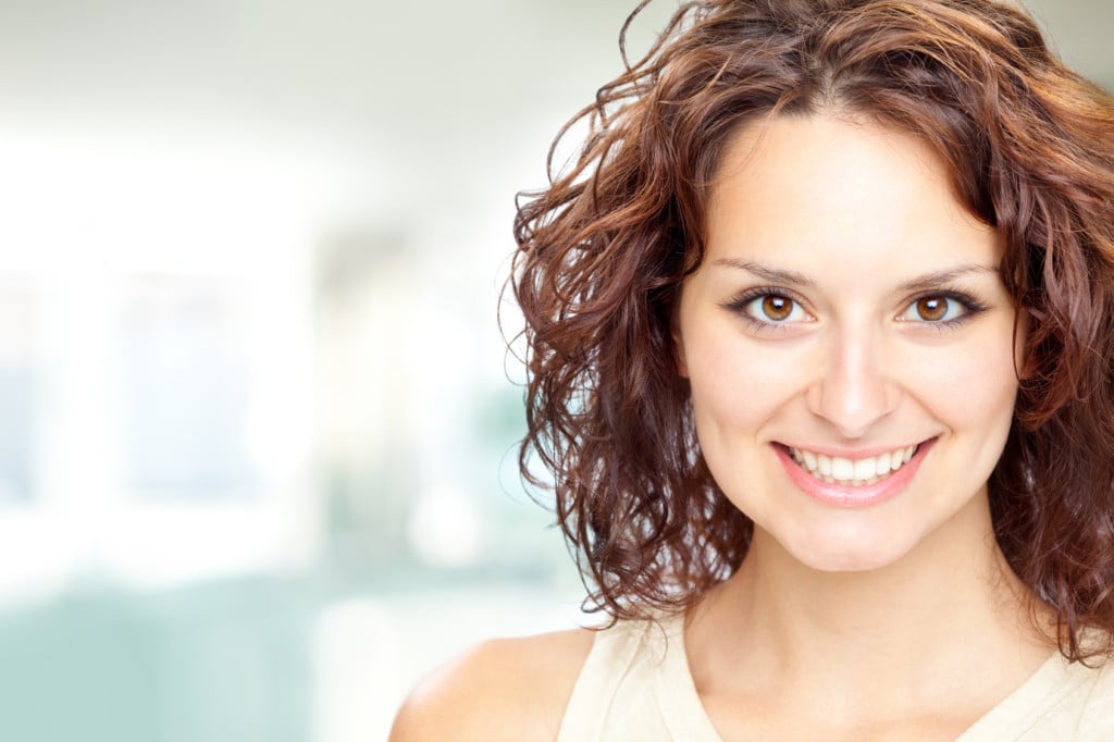 A woman smiling with new, straight teeth thanks to ControlledArch Orthodontics