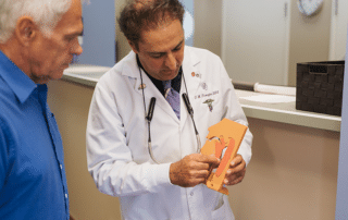 Dr. Firouzian using a model to show a patient why he is having problems