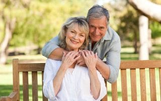 senior couple sitting on bench and hugging while outside