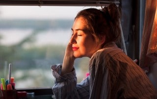 young woman allowing sunshine on her face at home