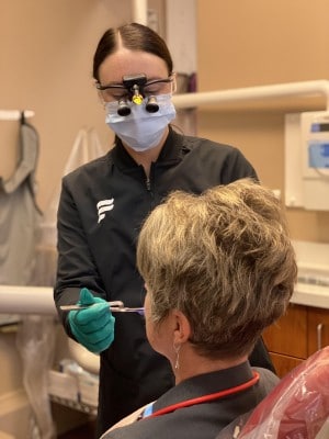 team member at Firouzian Dentistry inspecting the mouth of a dental implant patient 